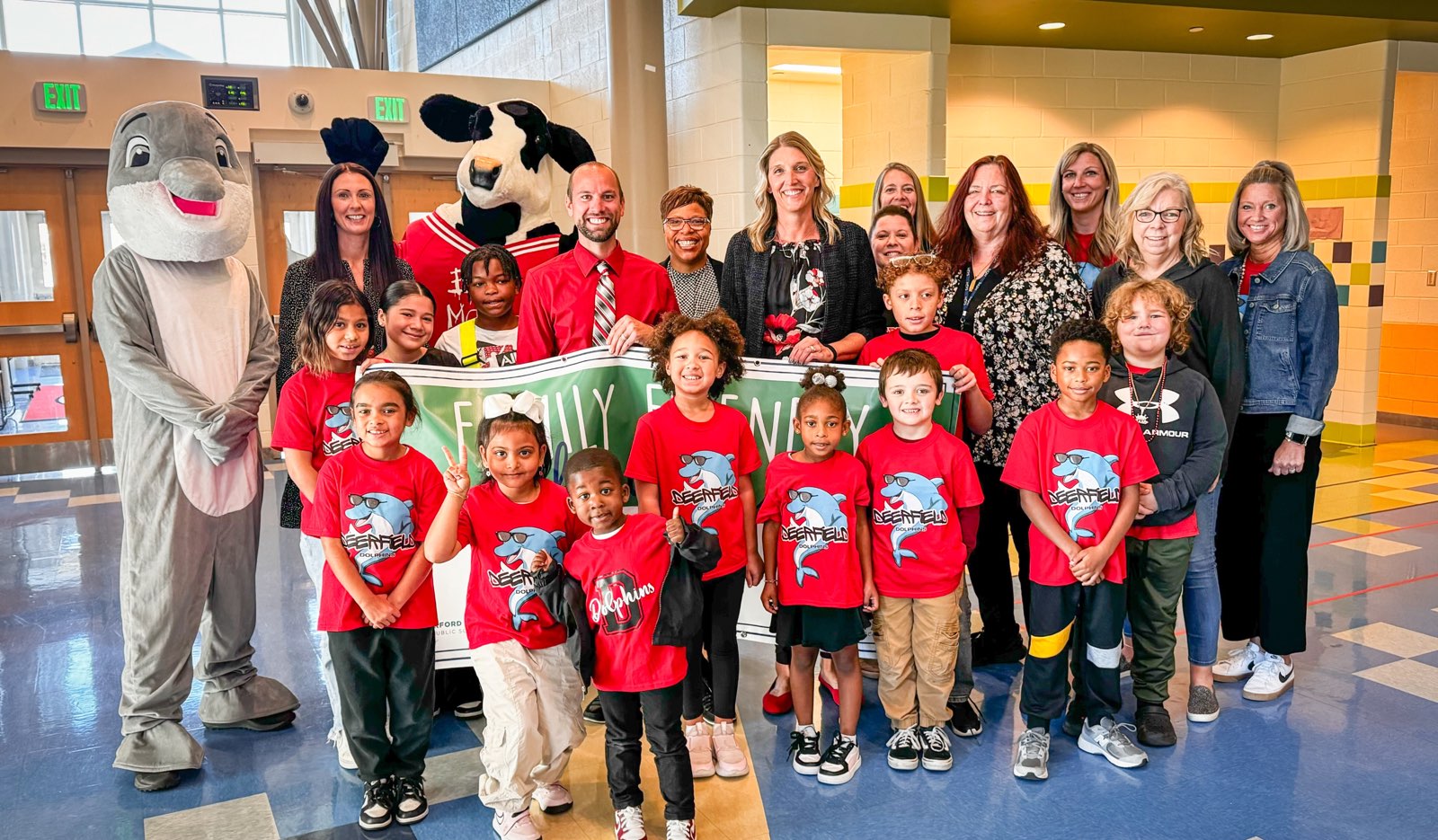 School system leaders, students, and mascots hold up Quarter 1 Family Friendly School Award banner.